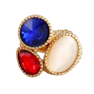 Anello vintage dorato con gemme blu, rosse sfaccettate e una pietra occhio di gatto bianca