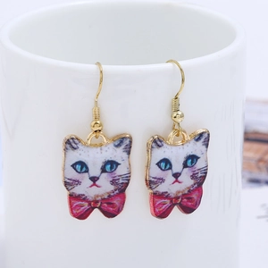 Detailed view of cat drop earrings with blue eyes and red bow on white ceramic cup