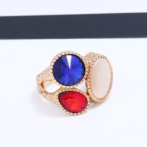 Dettaglio di un anello vintage dorato con pietre incastonate blu, rosse e beige
