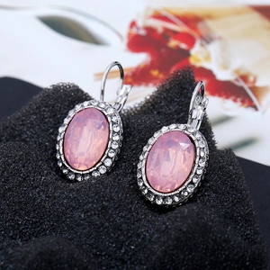 Detailed close-up of oval pink crystal earrings with silver lever-back clasps