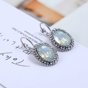 Detail view of oval white crystal drop earrings with leverback closures on card