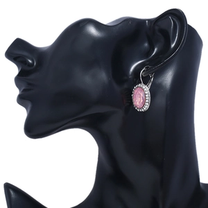 Close-up of vintage oval pink crystal earrings with halo diamonds on a black model