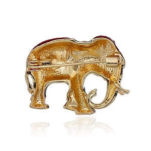 Elegant gold elephant brooch with red enamel and secure pin back on white background