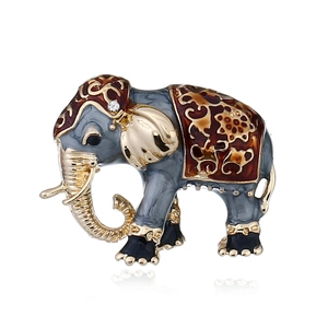 Exotic cloisonne elephant brooch with gold trim and red floral saddle on white background