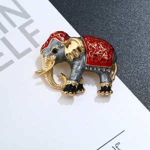 Macro detail of elephant brooch featuring grey enamel, gold plating and red patterns