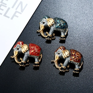 Close-up of vintage cloisonne elephant brooches with gold patterns on black background