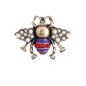 Macro shot of vintage bee brooch featuring pearl wings and red crystal abdomen