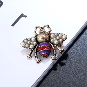 Close-up of vintage bee brooch with pearls and purple enamel details on a white card