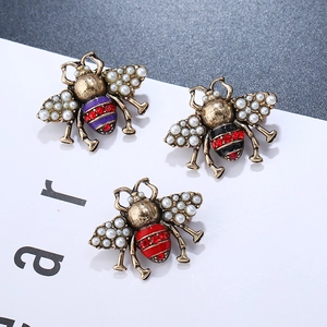 Detailed close-up of three vintage gold bee brooches with pearls and colorful rhinestones