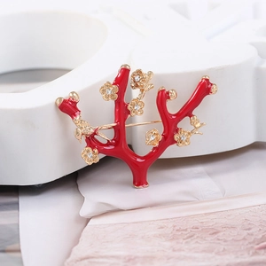 Macro detail of red coral branch brooch with gold plum blossoms and small bird