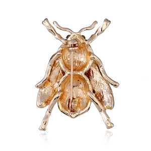 Detail view of insect brooch golden back side with safety pin clasp and textured metal