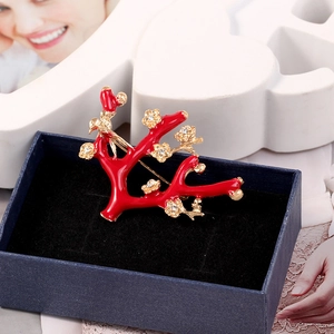 Detailed macro of red coral-style plum blossom brooch with crystals in gift box