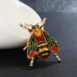 Macro side view of a gold insect brooch featuring vibrant enamel wings and lifelike detail