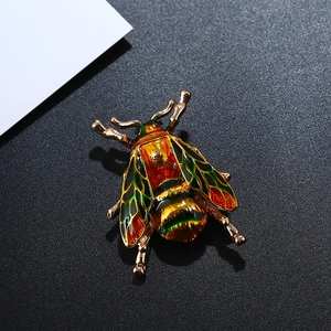 Detailed macro view of an ornate bee brooch with colorful enamel wings and golden finish