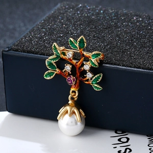 Détail de la broche arbre avec feuilles en émail vert, fleur violette et perle blanche