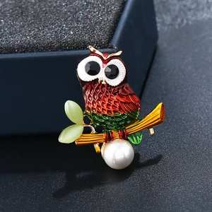 Close-up of owl brooch with red-green gradient enamel and a large white pearl detail