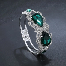 Detailweergave van zilveren armband met smaragdgroene waterdruppel edelstenen en kristallen