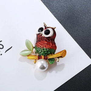 Detail of owl brooch with red-green enamel, cat eye leaves and white pearl drop