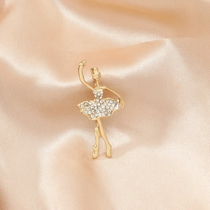 Elegant gold ballet dancer brooch with sparkling rhinestones on champagne satin background