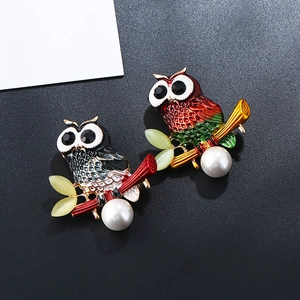 Detail of colorful owl brooches with white pearls and intricate enamel textures