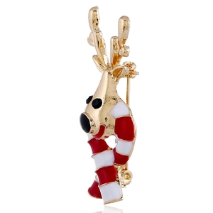 Macro detail of Christmas reindeer brooch with festive red and white enamel on golden alloy