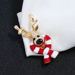 Close-up of a festive Christmas reindeer brooch with red scarf on white fabric texture