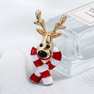Detailed view of a golden Christmas elk brooch with red striped scarf on knit fabric