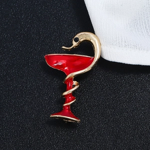 Makroaufnahme der vergoldeten Hygieia-Schale Brosche mit roter Emaille und Schlange
