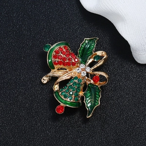 Close-up of a festive Christmas bell brooch with red and green rhinestones and a gold bow