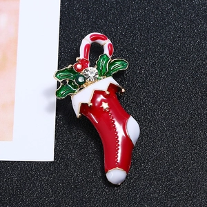 Detail of Christmas stocking brooch with enamel finish, candy cane and holly leaf details