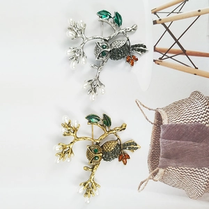 Detailed close-up of retro owl branch brooches with rhinestones and faux pearls