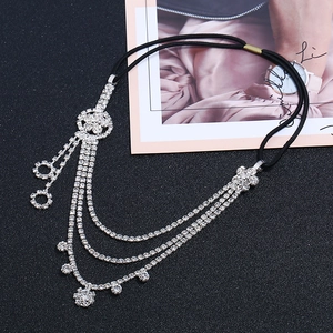 Detail of multi-layer sparkling rhinestone floral headband with silver chain on black surface