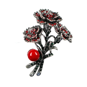 Detailed view of carnation brooch with red rhinestones and a red faux pearl drop