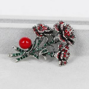 Detailed macro view of vintage floral brooch featuring red crystals and a large red pearl