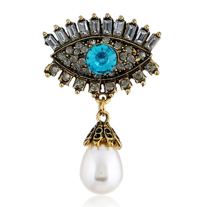 Detail of vintage gold evil eye brooch with blue crystal, rhinestones and drop pearl