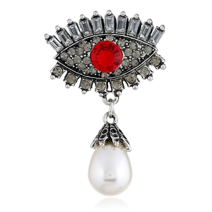Macro shot of evil eye brooch with red crystal, rhinestones and drop pearl detail