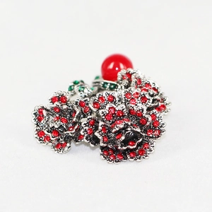 Detailed close-up of a vintage floral brooch with red rhinestones and silver metal finish
