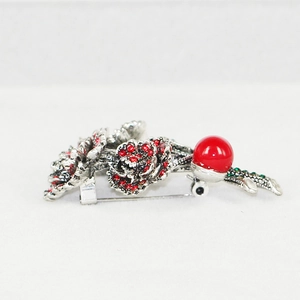 Detail of vintage silver flower brooch with red rhinestones and a large round bead