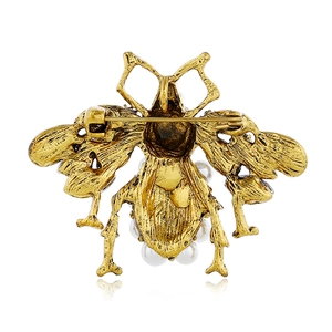 Close-up of vintage gold bee brooch back showing safety pin clasp and pearl accents