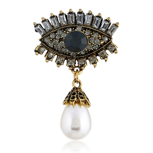 Macro shot of evil eye brooch with vintage gold finish, rhinestones and pearl drop