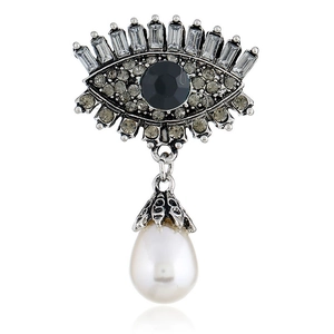 Detailed macro view of vintage silver evil eye brooch with rhinestones and pearl drop