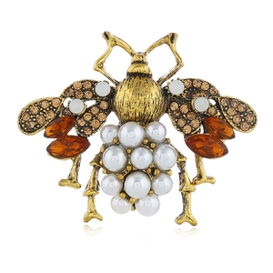 Macro shot of vintage gold bee brooch with white pearls and amber rhinestone wings
