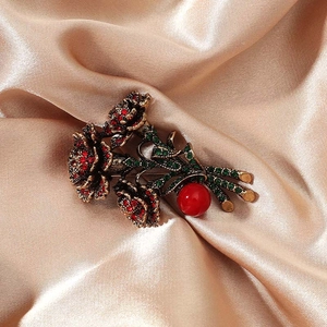 Vintage floral brooch with red and green rhinestones on elegant silk fabric background