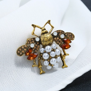 Detailed close-up of a vintage bee brooch featuring amber rhinestones and white pearls