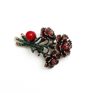 Vintage bronze flower brooch with red rhinestones and green crystal leaves on white background