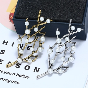 Vue détaillée de broches branche vintage en or et argent avec d'élégantes perles blanches