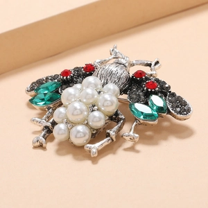 Vintage insect brooch featuring white faux pearls and green marquise gems on silver metal