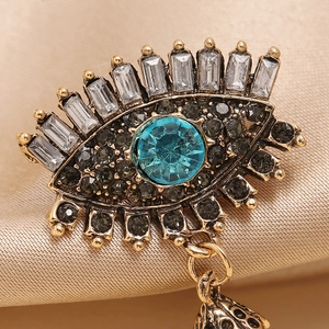 Retro evil eye brooch in antique gold with blue stones and pearls on silk background