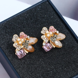 Elegant gold earrings with floral rhinestones, pearls, and purple crystals in a gift box