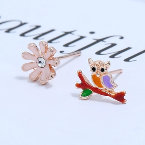 Detail of owl and daisy mismatched earrings with colorful enamel and rose gold plating